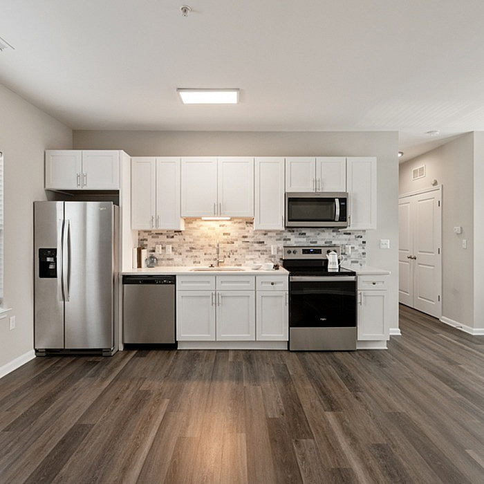 Modern kitchen with sleek stainless steel appliances, elegant white cabinetry, and a chic backsplash in a stylish open space.