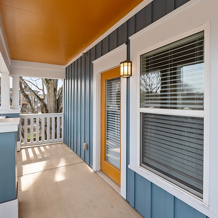 Charming covered balcony with vibrant orange accents, featuring modern design and inviting outdoor space.