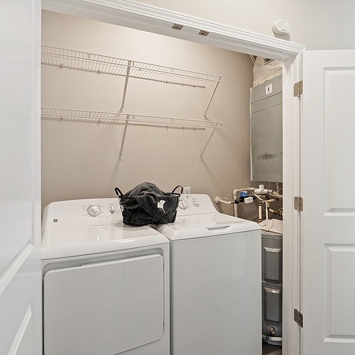 Bright and efficient laundry room with modern washer and dryer, featuring ample shelving space for storage.