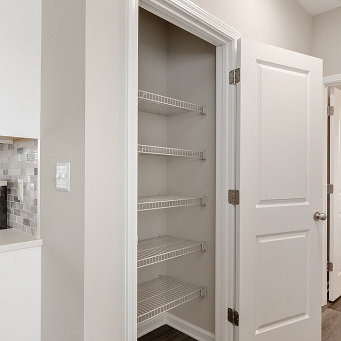 Modern apartment featuring a spacious pantry with sleek shelving, adjacent to a stylish kitchen with chic backsplash.