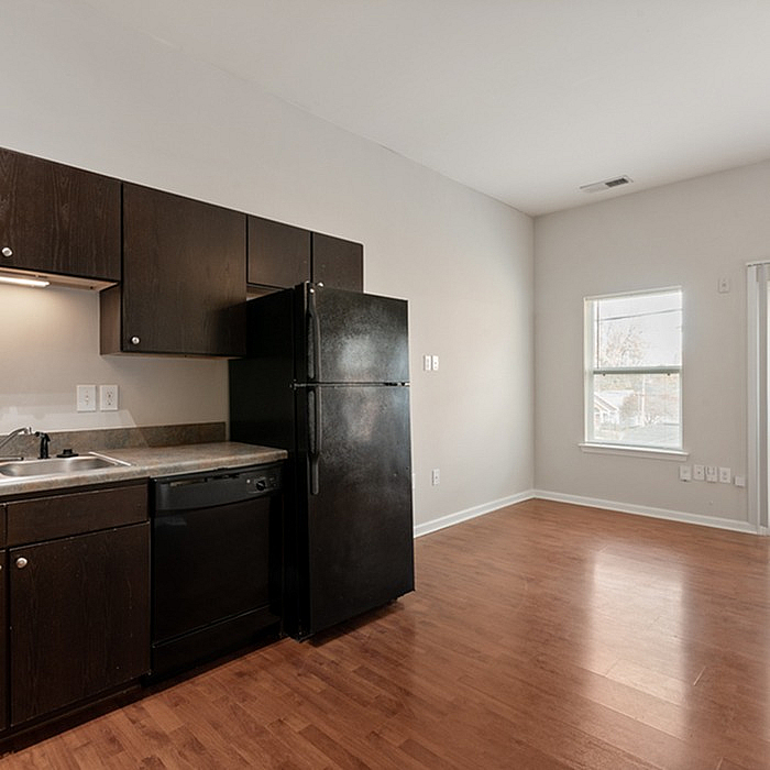 Sleek kitchen with modern dark wood cabinets, spacious countertops, and natural light from a large window.