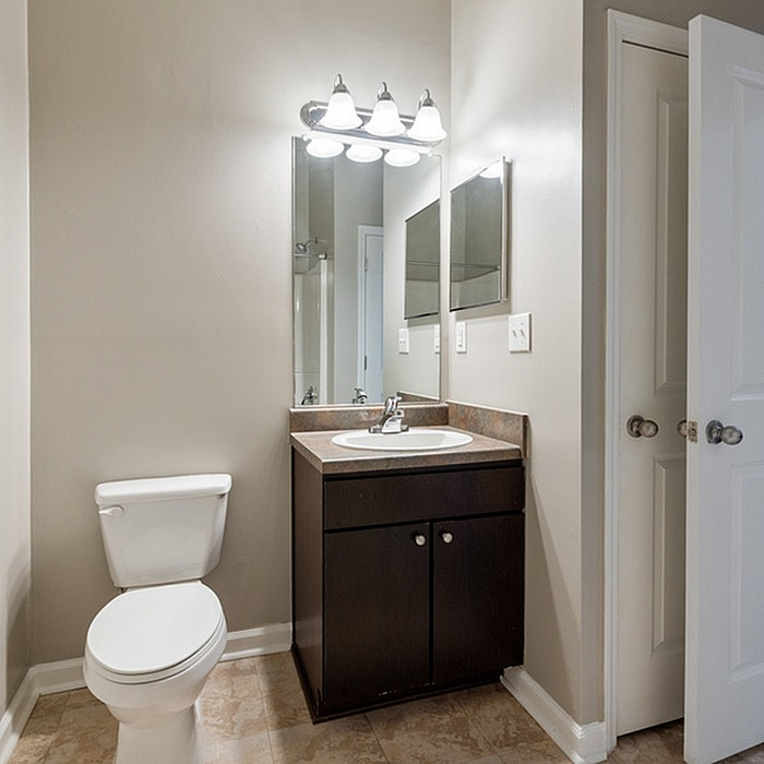Bright and modern bathroom with sleek fixtures, featuring a large mirror, elegant vanity, and pristine white toilet.