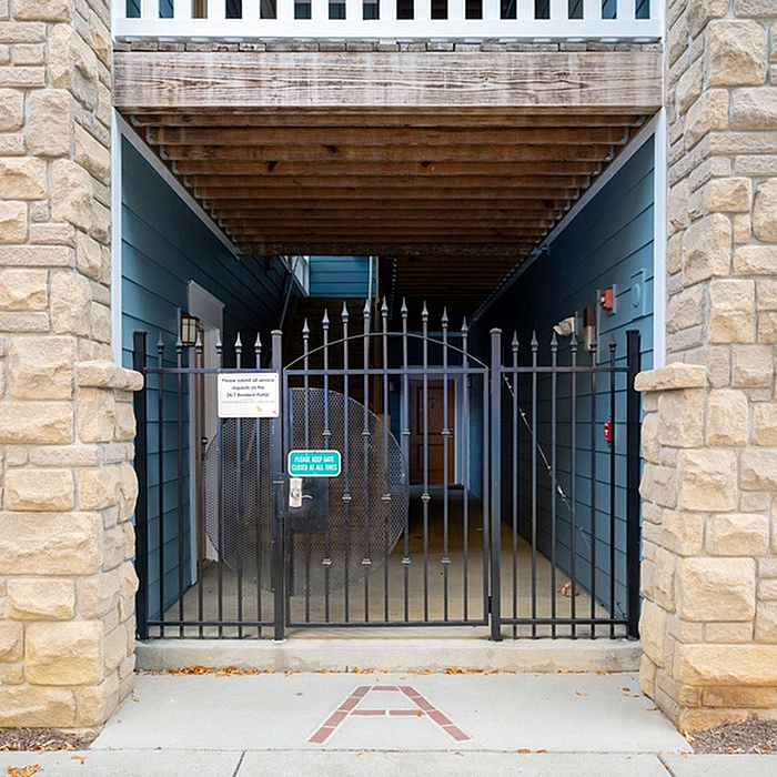 Charming entryway with a stylish black wrought iron gate and rustic stone walls, offering a welcoming and secure entrance to the property.