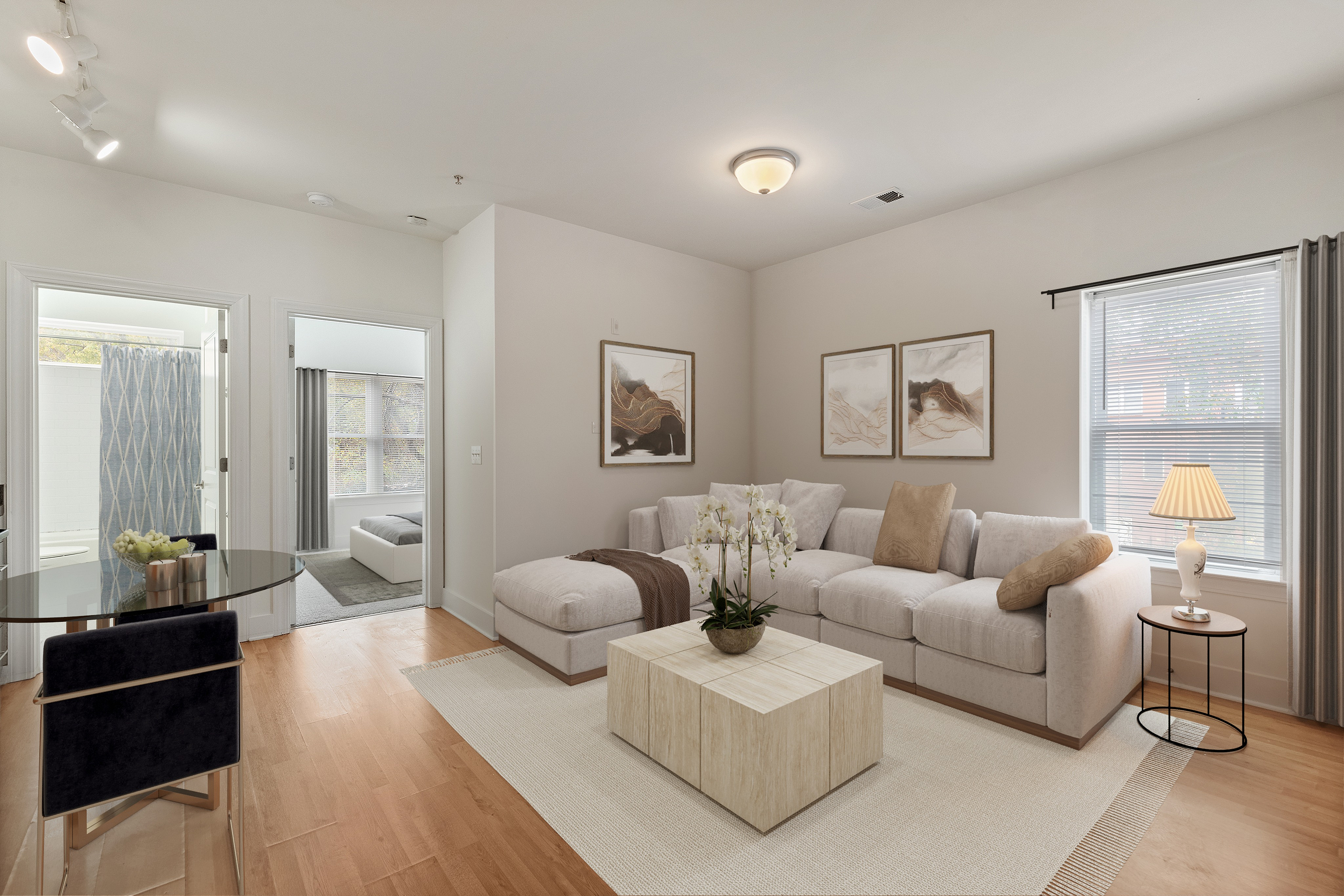 Bright, airy apartment living room with a cozy sectional sofa, stylish wooden coffee table, and abstract wall art, featuring natural light from large windows.