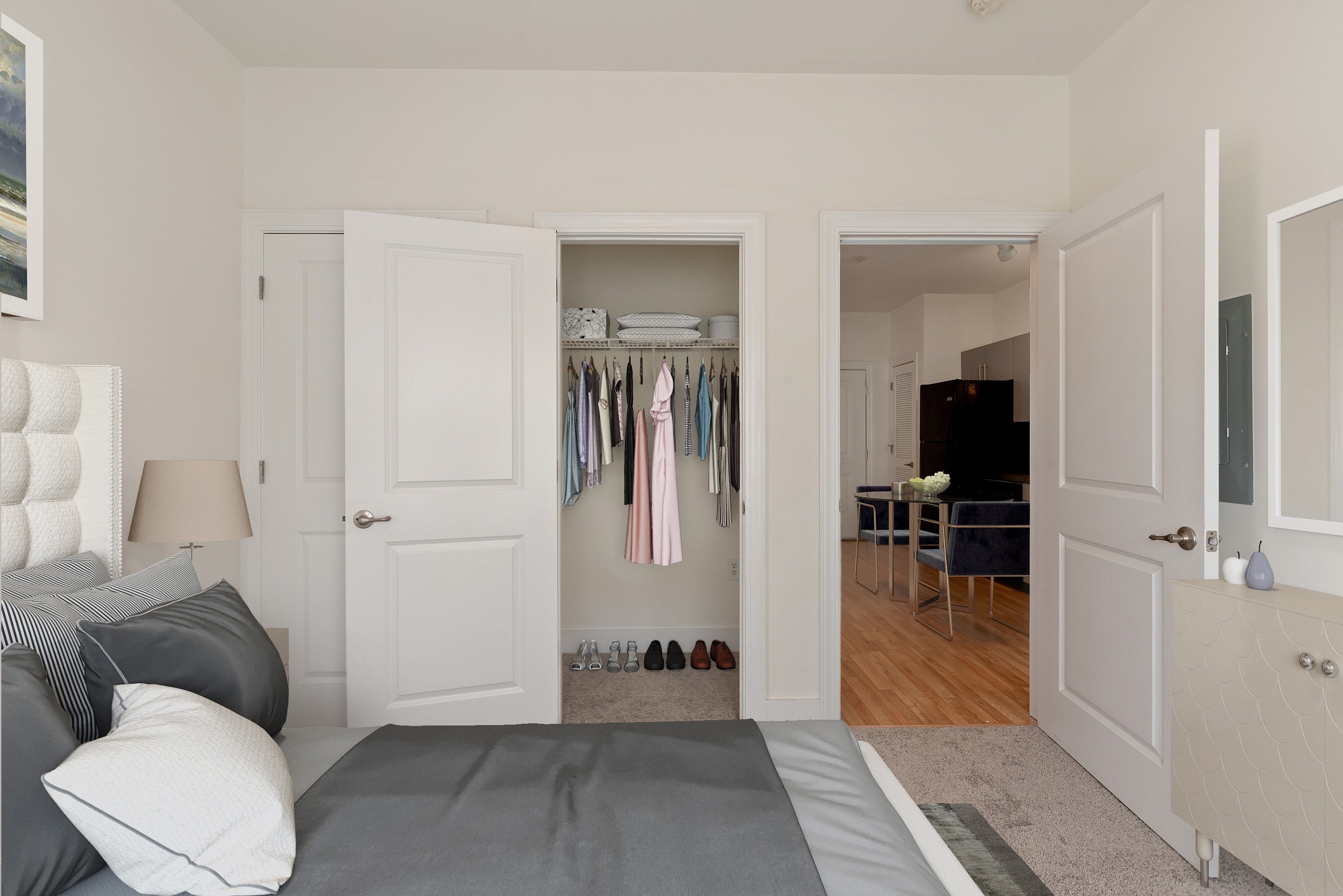 Inviting bedroom with plush bedding, ample closet space, and a view into the modern dining area with elegant decor and open layout.