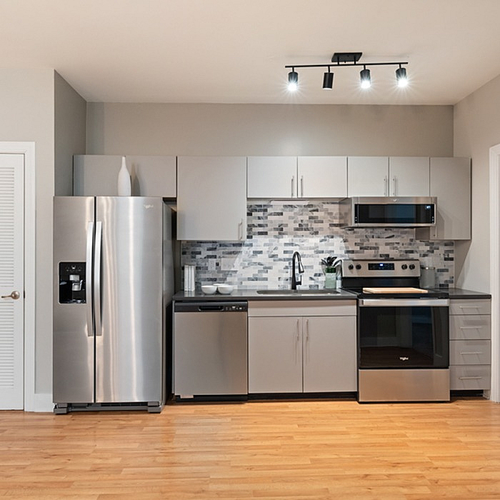Modern kitchen with sleek stainless steel appliances, elegant tile backsplash, and stylish cabinetry on hardwood flooring.