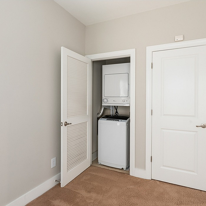 Bright modern space featuring a convenient in-unit laundry closet with a sleek stacked washer and dryer.