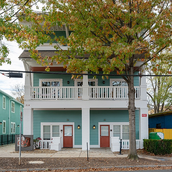 Charming duplex with lovely green facade and inviting balconies, surrounded by vibrant autumn foliage.