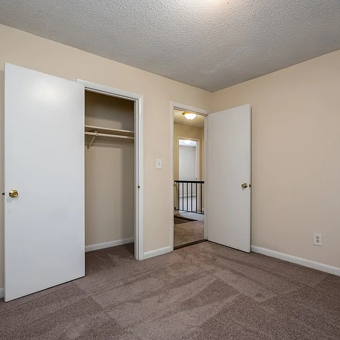 Bright bedroom with plush carpeting and spacious closet in modern apartment.