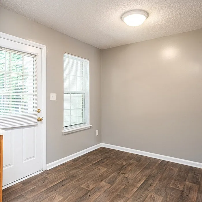 Bright room with elegant hardwood floors, neutral walls, and ample natural light from large windows, perfect for cozy living space.