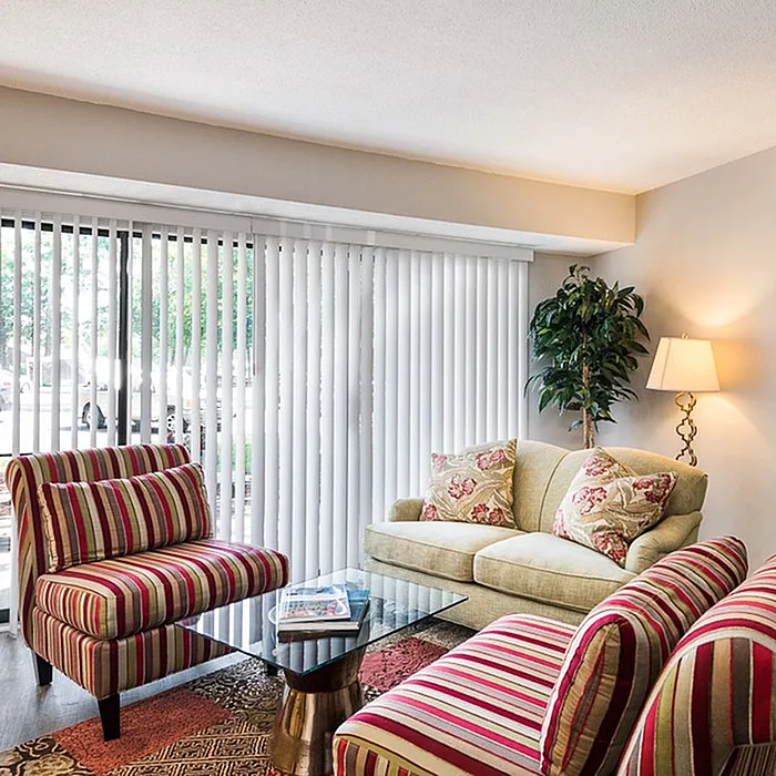 Charming living room with stylish striped chairs, cozy sofa, large window with blinds, and elegant decor.