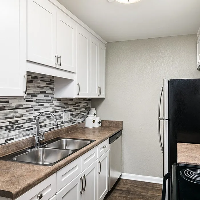Modern kitchen with sleek stainless steel appliances, elegant backsplash, and pristine white cabinetry.