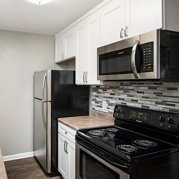 Modern kitchen with sleek stainless steel appliances, elegant tile backsplash, and bright white cabinetry.