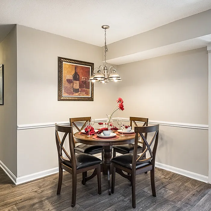 Elegant dining area featuring a round wooden table set for four with stylish decor and ambient lighting.