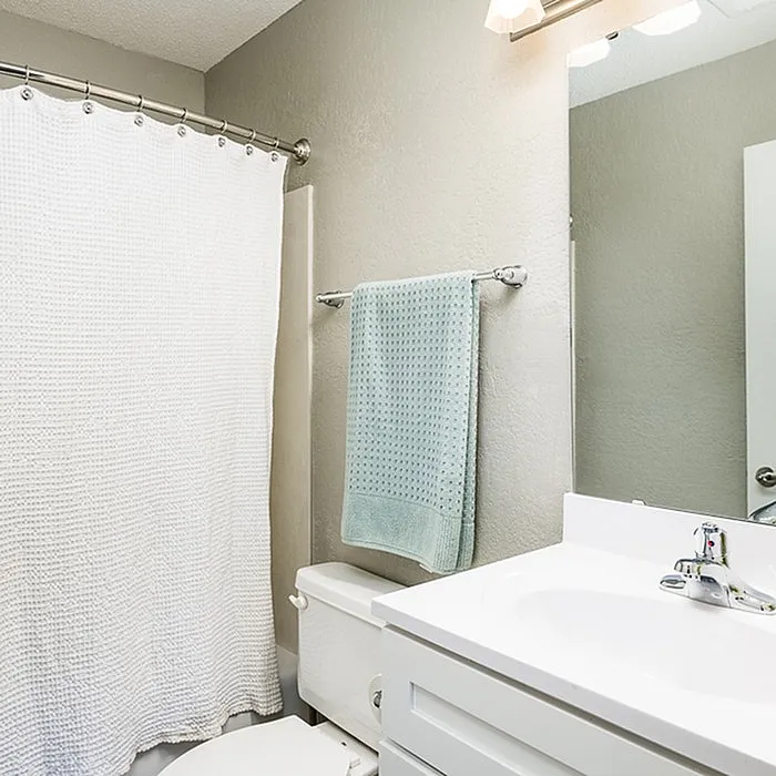 Bright and modern bathroom with elegant fixtures, featuring a chic vanity, soft lighting, and a tasteful shower curtain.