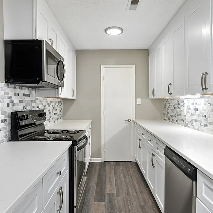 Modern kitchen with sleek white cabinets, stainless steel appliances, and stylish mosaic backsplash.