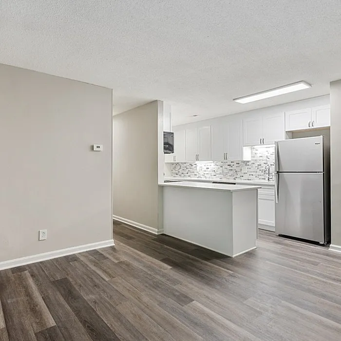 Modern kitchen design with sleek white cabinets, stainless steel appliances, and elegant hardwood flooring creating a spacious and inviting atmosphere.