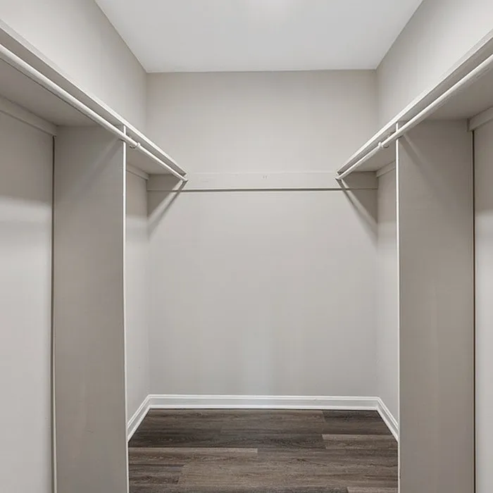 Spacious walk-in closet with modern shelving and elegant wood flooring, ideal for organized living.