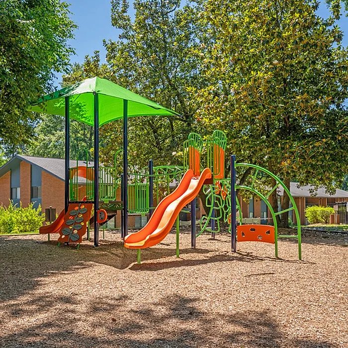 Inviting playground with vibrant slides and climbing structures surrounded by lush greenery for family fun.