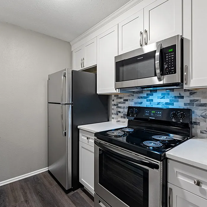 Modern kitchen with sleek stainless steel appliances, elegant white cabinetry, and stylish tile backsplash.