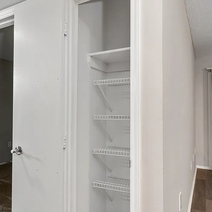 Modern apartment with a spacious utility closet featuring multiple shelves, perfect for organization.