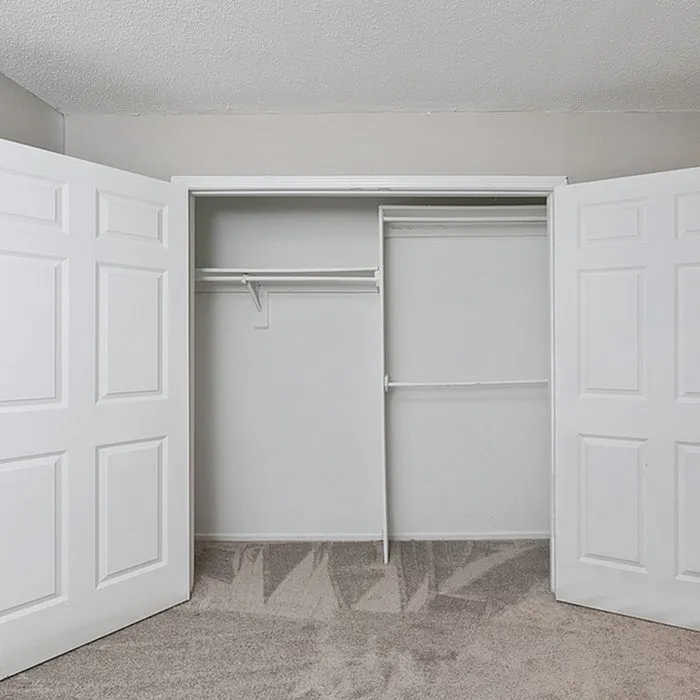 Spacious and modern walk-in closet with white double doors and sleek interior shelving, perfect for organized living.