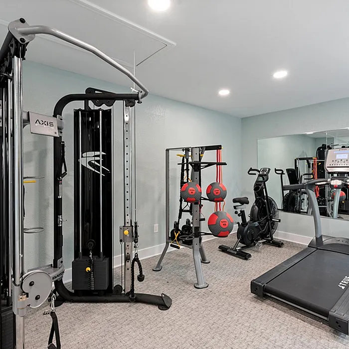 Modern apartment gym featuring cutting-edge fitness equipment, including a treadmill, exercise bike, and weight machine for a complete workout experience.