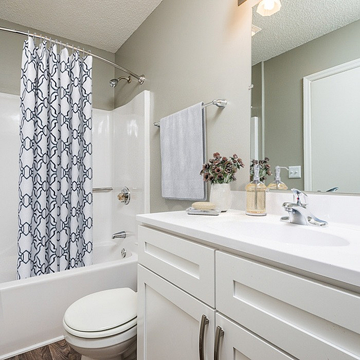 Modern bathroom featuring a sleek white vanity, stylish shower curtain, and elegant decor for a serene atmosphere.