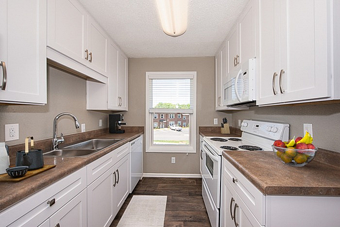 Elegant kitchen with modern white cabinets, sleek countertops, and a bright window view, ideal for culinary enthusiasts.
