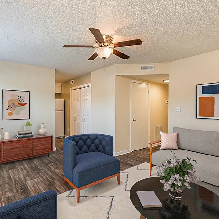 Chic living room with elegant blue chairs, modern ceiling fan, and stylish decor, offering a welcoming ambiance.