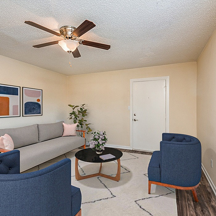 Charming living room with modern décor, featuring a cozy gray sofa, elegant blue chairs, and chic artwork. Inviting atmosphere with soft lighting and stylish furnishings.