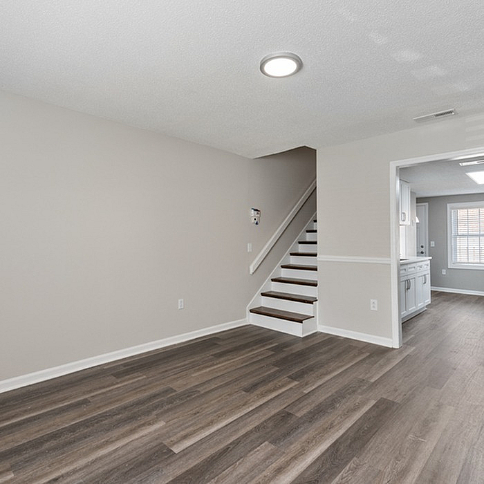 Modern apartment interior featuring sleek hardwood floors, a cozy staircase, and an inviting open-concept kitchen with ample natural light.