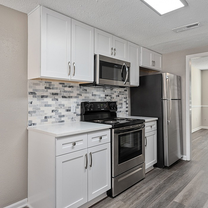 Modern kitchen with sleek stainless steel appliances, elegant white cabinetry, and a stylish tile backsplash.