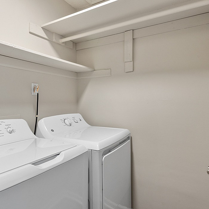 Modern laundry room with high-efficiency washer and dryer set, featuring ample shelving for storage.