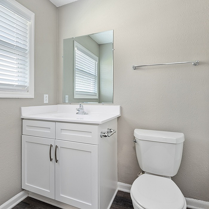 Bright and modern bathroom featuring a sleek white vanity, mirror, and natural lighting.