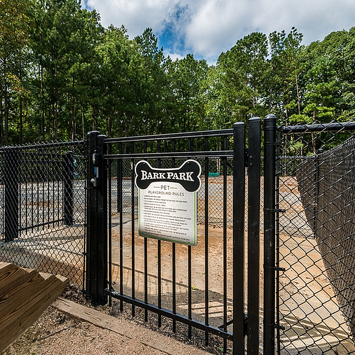Inviting gated entrance to a serene bark park surrounded by lush greenery, perfect for pet-friendly communities.