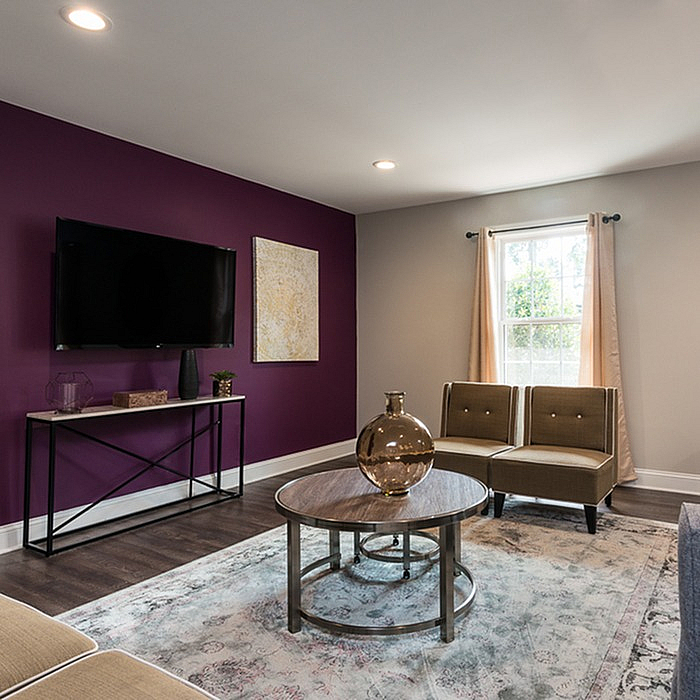 Inviting living room with modern decor, featuring a vibrant purple accent wall, sleek furniture, and abundant natural light.