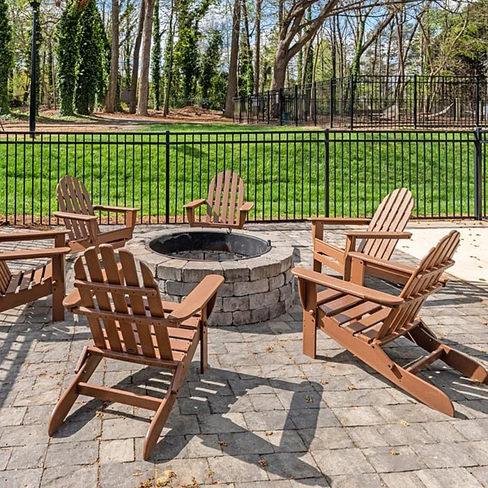 Charming outdoor patio with cozy Adirondack chairs surrounding a stone fire pit, perfect for social gatherings.