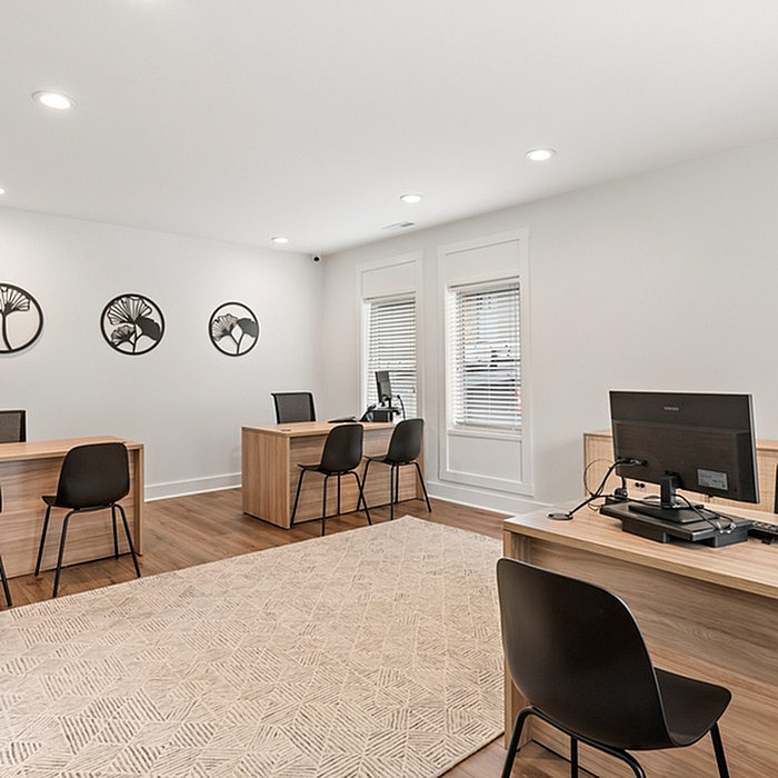 Modern and bright office space featuring sleek wooden desks, comfortable black chairs, and elegant wall decor, perfect for a productive work environment.