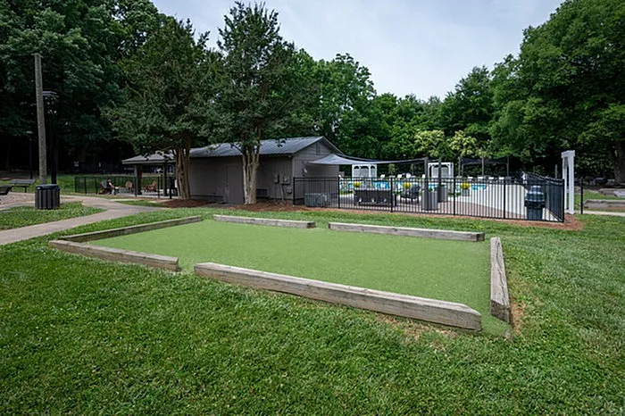 Charming outdoor recreation area featuring a manicured bocce ball court and a nearby swimming pool in a lush green setting.