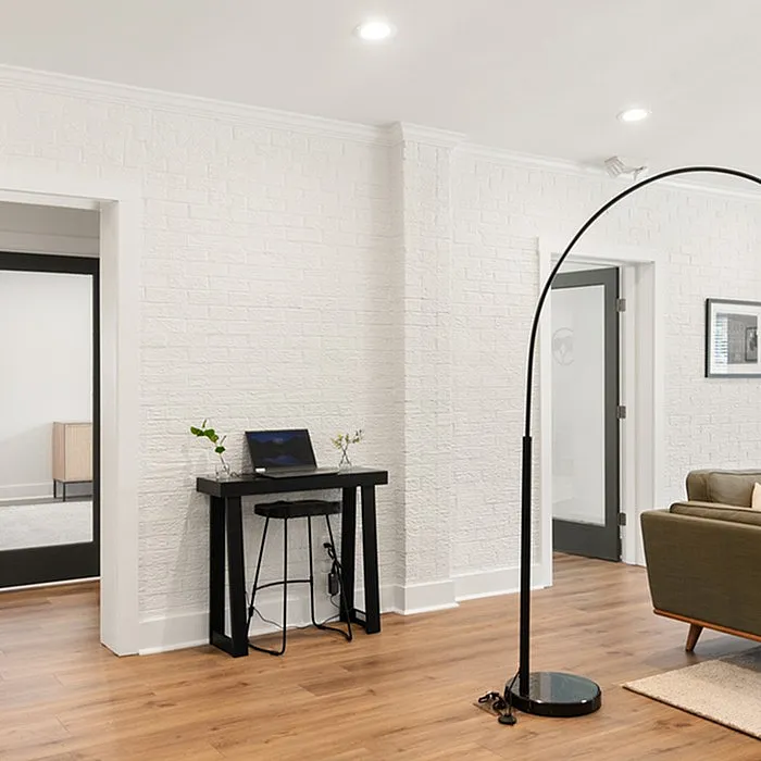 Chic apartment interior featuring a modern white brick wall, sleek black furnishings, and warm wood flooring.