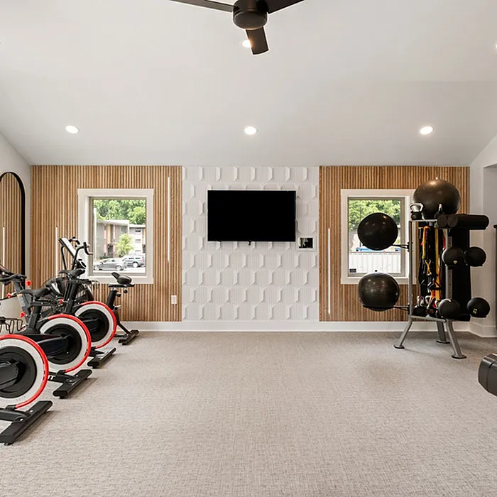 Modern home gym with stylish wall decor, equipped with exercise bikes and fitness equipment, offering a vibrant workout space.