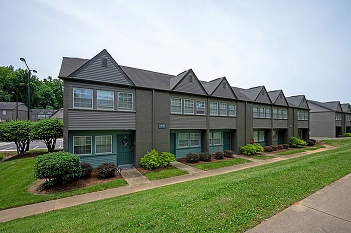 Charming townhouse row with modern gray exterior and lush green landscaping, perfect for family living.