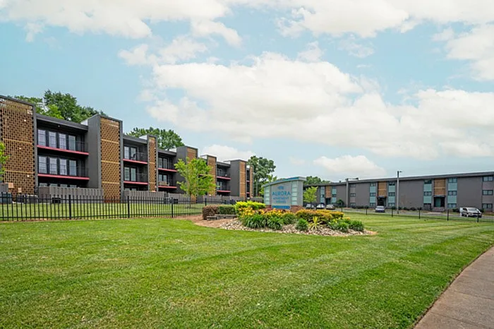 Modern apartment complex with lush green lawns and a stylish architectural design under a clear blue sky.