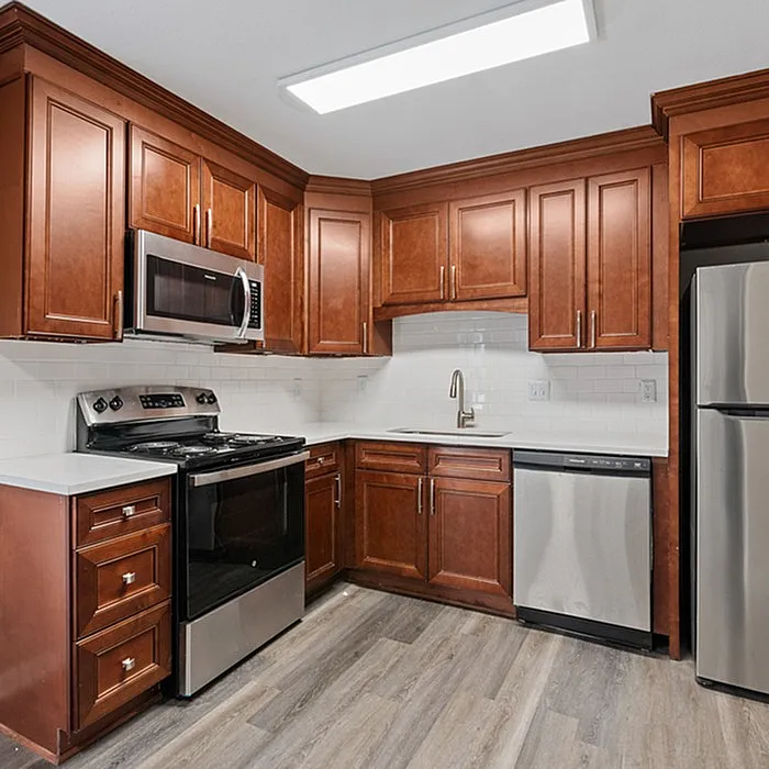 Elegant kitchen with rich wood cabinetry, modern stainless steel appliances, and sleek white countertops.