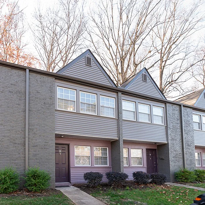 Charming two-story apartment exterior featuring modern architecture with large windows and a landscaped front yard.
