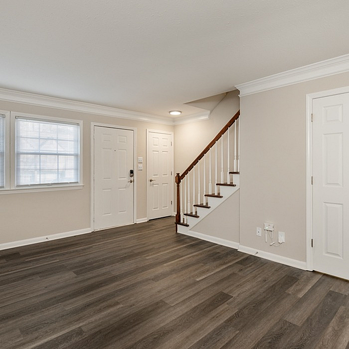 Inviting entryway with elegant wood flooring and a staircase, ample natural light through large windows, and modern neutral decor.