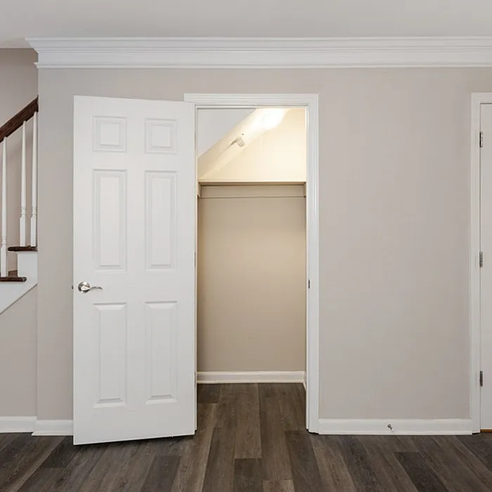 Inviting apartment featuring a modern closet with elegant flooring and a sleek staircase detail.