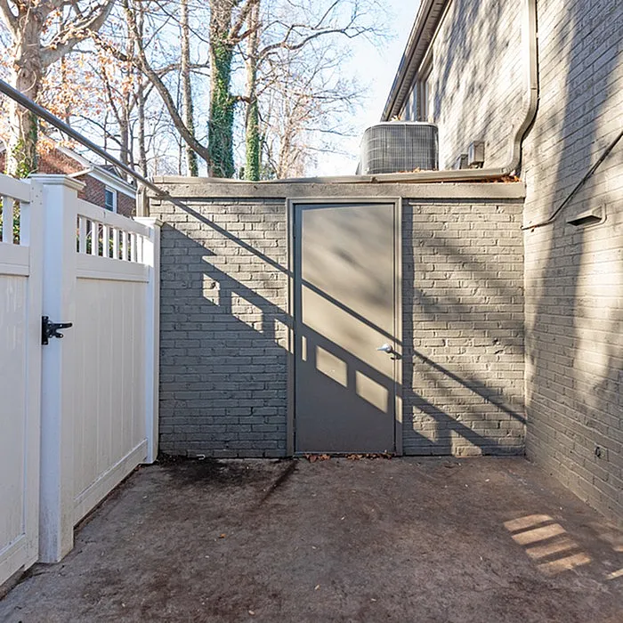 Chic and private outdoor space with modern brick facade, featuring a secure door and stylish white fence, perfect for urban living.