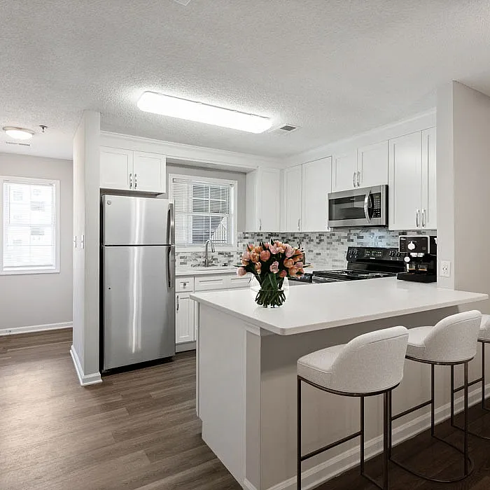 Bright contemporary kitchen with stainless steel appliances, sleek white cabinetry, and a cozy breakfast bar adorned with fresh flowers.